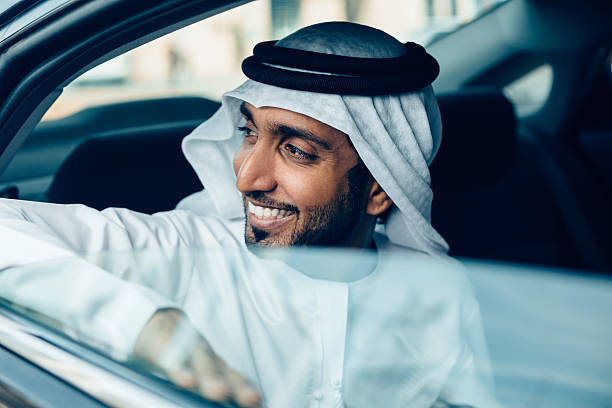 A smiling man in traditional attire looks out of a car window, symbolizing the benefits of RAKEZ Free Zone.